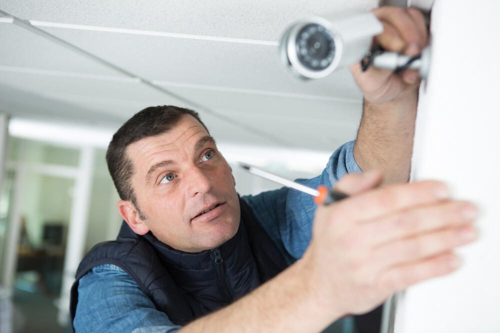 Technician fitting a CCTV camera in an office